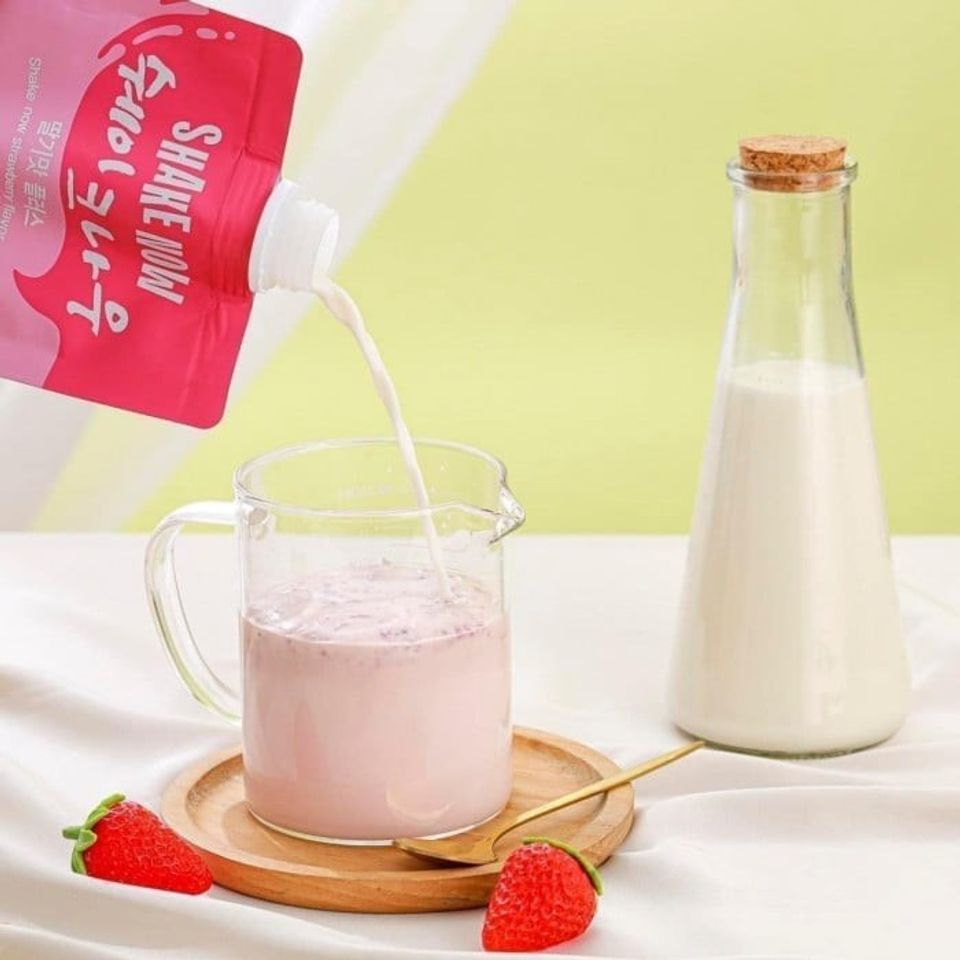 A strawberry milk being poured into a glassDescription automatically generated